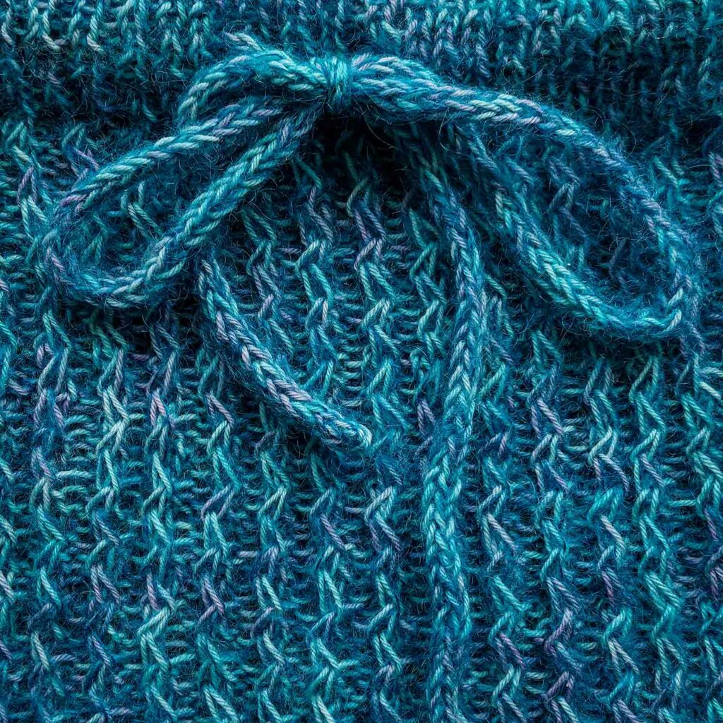 close up view of the front of the Quinzhee cowl showing the I-cord tie and zigzag cable pattern