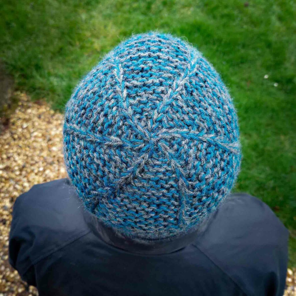 view of the garter squish beanie from the top, showing the crown which has slip stitches swirling out from the centre and the main hat is knit in garter stitch