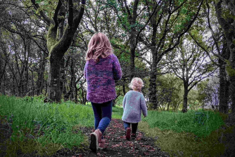 back view of two children wearing the garter squish kids jumper. on show is the all over garter stitch pattern and dropped back hems