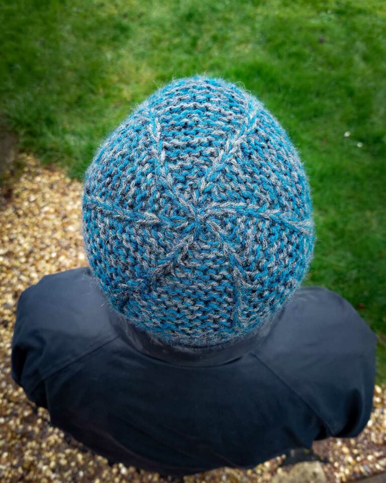 view of the garter squish beanie from the top, showing the crown which has slip stitches swirling out from the centre and the main hat is knit in garter stitch