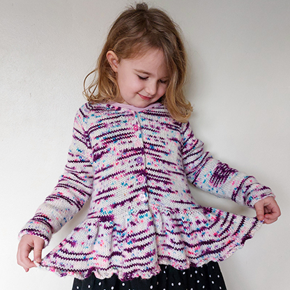 front view of the flutterbye cardigan knit in hand dyed yarn. the cardigan has an i-cord neckline, integrated icord button bands and a frilled peplum bottom, separated from the main body by a lateral (vikkel/estonian) braid